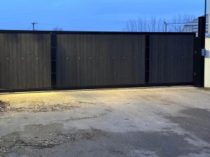 Large automated commercial sliding gate with dark composite infill panel installed by Security Gates and Doors