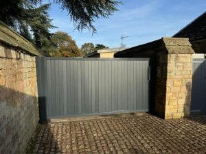 Automated grey aluminium sliding gate installed at Thorpe Hall between stone pillars by Security Gates and Doors